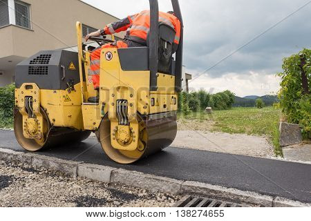 Worker at asphalting works with road roller