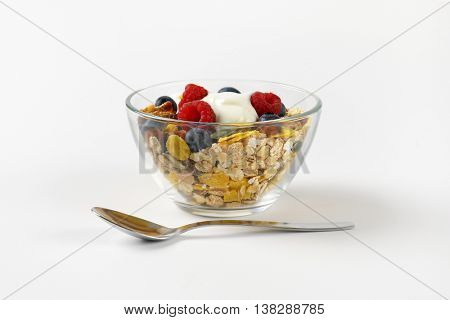 bowl of cereals with berry fruit and white yogurt on off-white background with shadows