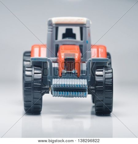 Small red toy tractor on light background, shallow depth of field