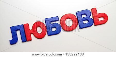 Russian language, the word love is laid out from plastic letters with a magnet. Cyrillic.