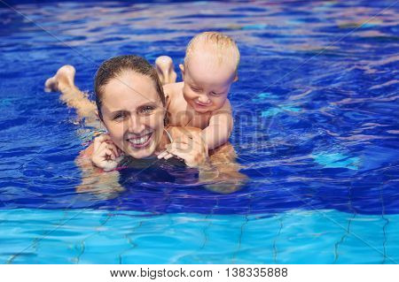 Funny happy family - mother baby son learn to swim sunbathing with fun in beach pool. Healthy lifestyle active parent people water sports activity and swimming lessons on summer holiday with child