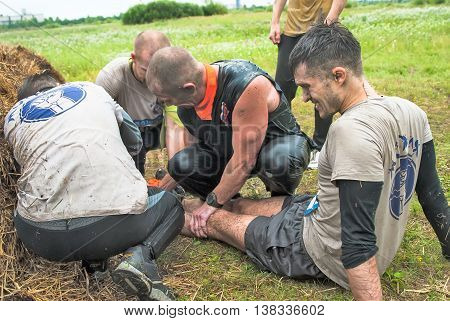 Tyumen, Russia - August 8, 2015: Steel Character extrim race on Krugloe lake. Gagarin park in Cape district. Members of team give first aid to companion after unsuccessful attempt at stage