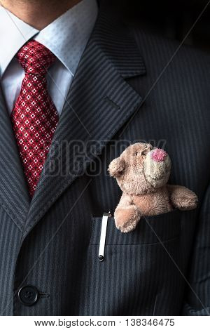 The elegant stylish businessman keeping cute teddy bear in a his breast suit pocket. Formal negotiations concept.