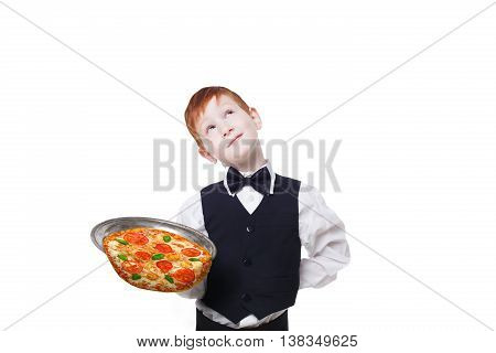 Clumsy little waiter drops tray with pizza while dreaming. Food falling down. Redhead child boy in suit shows inattentive waiter failure at white background