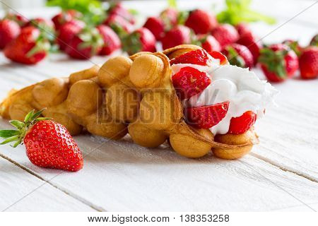 waffles with strawberries and whipped cream on the wooden table