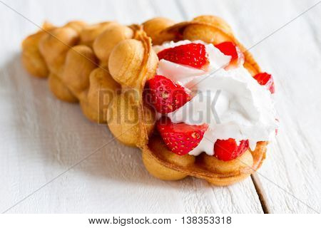 waffles with strawberries and whipped cream on the wooden table