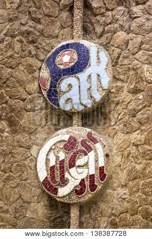 BARCELONA, SPAIN - APRIL 28 2015: An emblem for Park Guell formed out of ceramic tiles as seen on an exterior walll that surrounds the park. The park in Barcelona was designed by Antoni Gaudi.