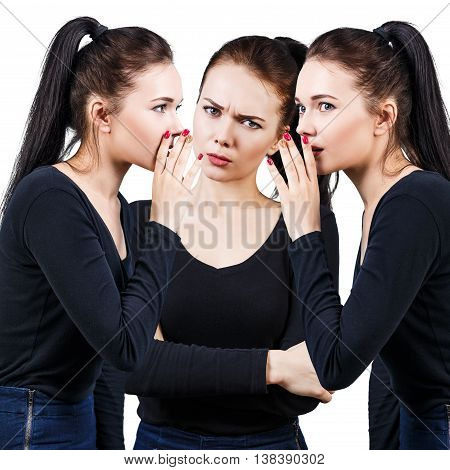 Brunette girls telling gossip to another angry girl isolated on white