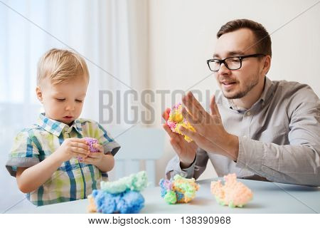 family, childhood, creativity, activity and people concept - happy father and little son playing with ball clay at home