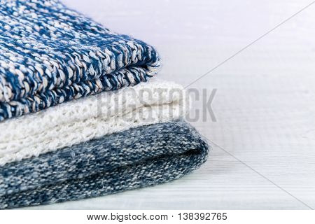 Wool socks and stack of various sweaters. Winter style. On a wooden table, handmade