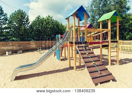childhood, equipment and object concept - climbing frame with slide on playground outdoors at summer