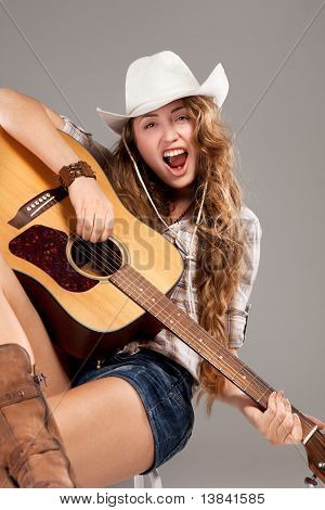 Sesy vaquera en el sombrero de vaquero con guitarra acústica