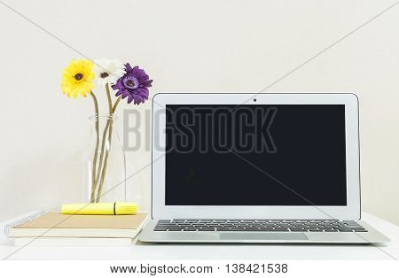 Closeup computer notebook on blurred white wood desk and cream color wallpaper wall in room texture background beautiful work place interior of house concept
