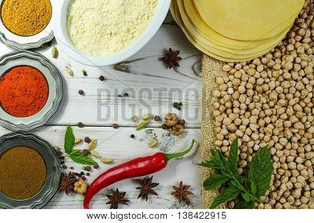 Colorful Indian food - papadum chickpea ginger gram flour and spices on white wooden table top