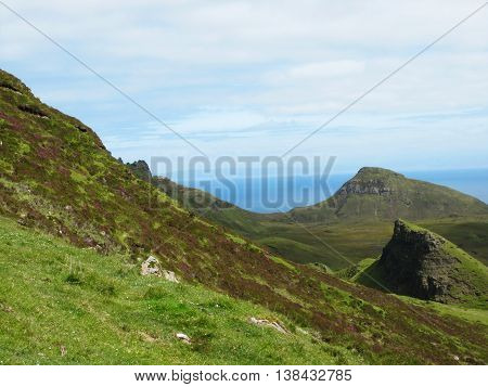 Rolling green hills with blooming heather on the Isle of Skye.