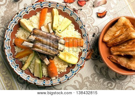 Traditional couscous dish with lamb ribs and vegetables. Top view. The image is describing moroccan culture