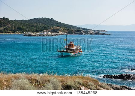 Ship is sailing to small Sarti harbor, mount Athos in background, Sithonia, Greece