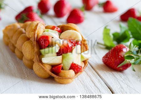 waffles with fruits strawberries apple and kiwi on the wooden table