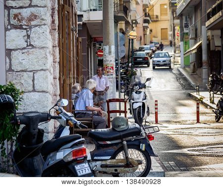 SITIA, CRETE, GREECE - JUNE 28, 2016: Old man sit on chairs at the street and talk about life in Sitia town
