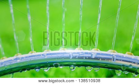 Lawn sprinkler spaying water over green grass. Motion blur. Select focus.