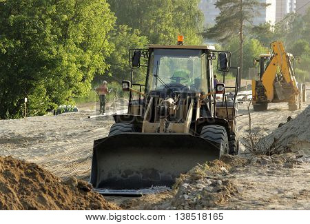 bulldozer, forklift and workers at the construction road junction in Moscow region