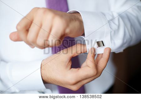 Elegant young fashion man fixing his cufflinks closeup