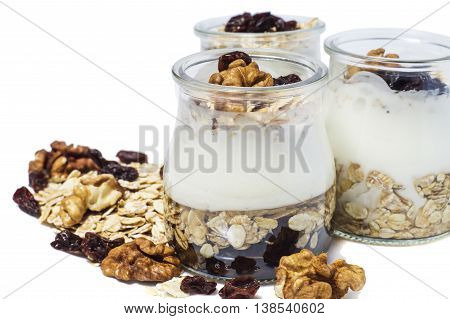 Healthy breakfast - yogurt with dried fruits honey and nuts and muesli served in glass jar isolated on white. Healthy lifestyle.