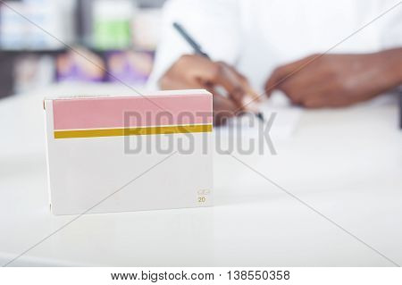 Black pharmacist or doctor writing with green tablet package with copy space