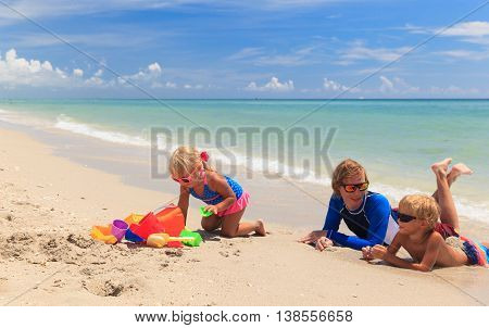 father with son and daughter play on summer beach