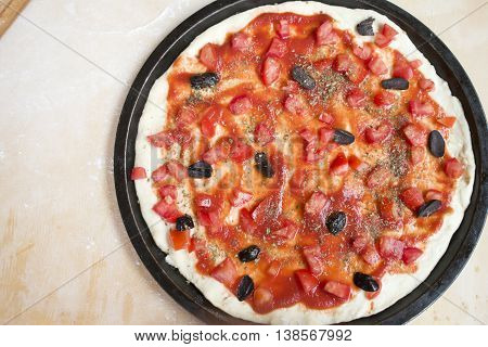 flat lay of pizza with fresh tomato and black olives with near a rolling pin