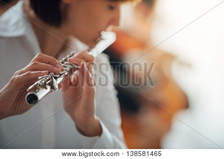 Professional female flute player performing with classical music symphony orchestra unrecognizable person
