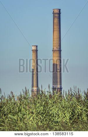 Factory with tall chimneys. Power plant chimneys tower in Bucharest city view from Vacaresti Nature Park.