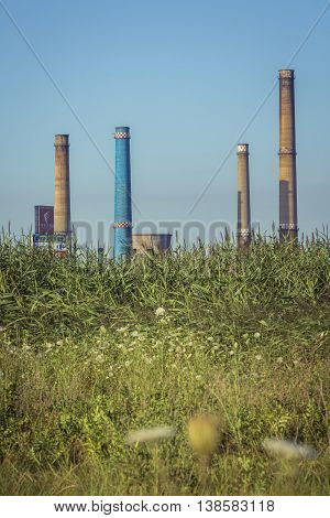 Factory with tall chimneys. Power plant chimneys tower in Bucharest city view from Vacaresti Nature Park.
