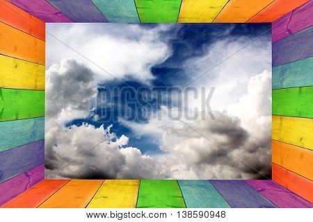 multicilored frame on the dark blue sky background with great white clouds