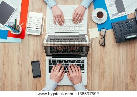 Man and woman working at office desk with customized different workspaces the woman's side is full and the man's side is clean and simple