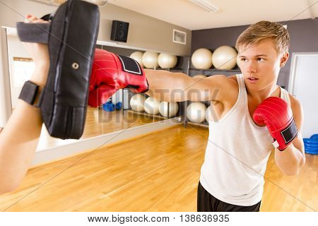 Two young and focused people trains boxing in pairs. Sparring as workout at the fitness gym.