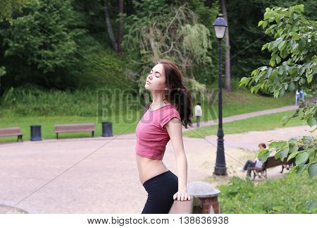 Profile portrait of happy young sporty woman relaxing in park. Female relaxing breathing fresh air outdoors.