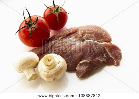 a piece of meat, white background, parsley, tomatoes and mushrooms