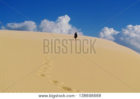 Man walking bare feet on a sand dune