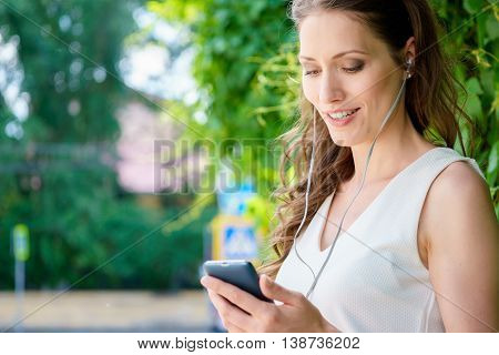 Portrait of young brunette caucasian woman with mp3 player in park