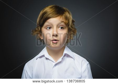 Closeup Portrait of handsome boy with astonished expression while standing against grey background.