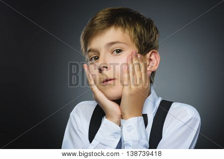 Closeup Portrait of handsome boy with astonished expression while standing against grey background.