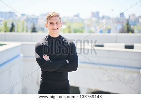 Portrait of a smiling male athlete on the background of the city