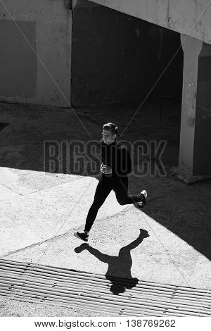 Black-and-white photo of an athlete running in the wall of the city