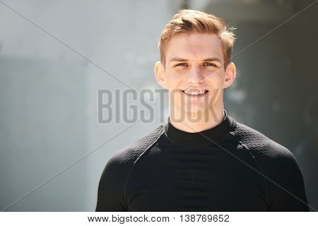 Portrait of smiling athlete male in a black skin-tight clothes