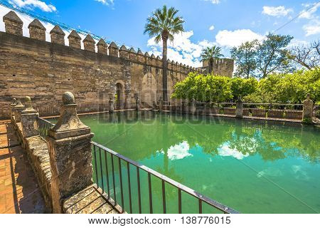 Decorative green pool around the military fortress The Alcazar de los Reyes Cristianos in a sunny day. Cordoba, Andalusia, Spain.