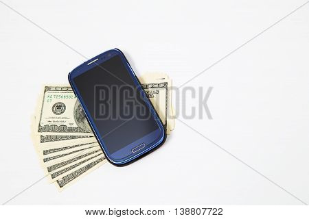 Smartphone lying on the United States dollars, isolated on a white background