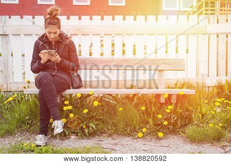 Hipster beautiful woman texting her mobile to another women in sunset between yelow flower by vintage style.
