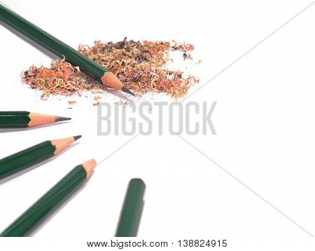 five sharpened and unsharpened green pencils with pencil sawdust