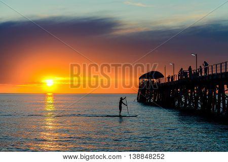 Standup paddleboarding silhouette of a man at Henely Beach near the jetty South Australia